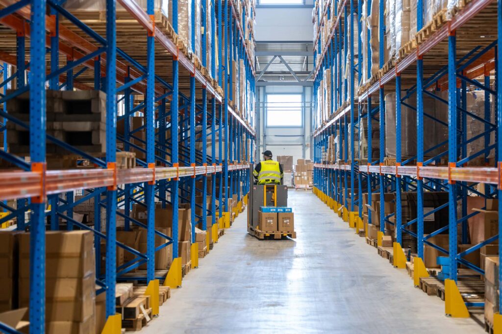 Foto av mann som sitter på truck i lager for tredjepartslogistikk. logistikk
